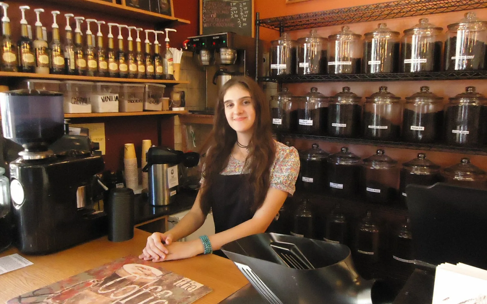 Coffee shops use warm colors such as browns and oranges in counter displays. In photo, a cashier at Ahrre's Coffee Roastery in Summit, New Jersey. Coffee shop compliance checklist: questions to ask